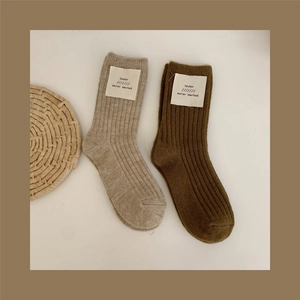 Detail of ribbed wool socks featuring vintage cloth labels in beige and brown colors
