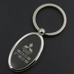 Detail of Mitsubishi Motors metal keychain with oval black pendant on black background