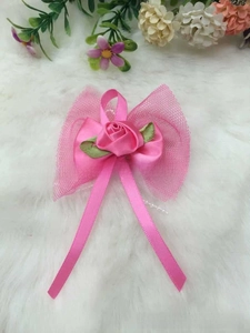Close-up of handmade pink ribbon flower with green leaves and tulle mesh detail
