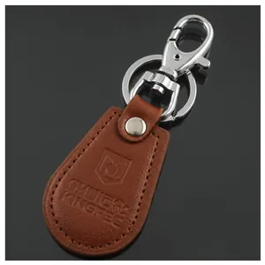 Close-up of brown leather keychain with metal snap hook and embossed car brand logo