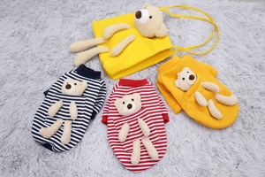 Detailed flat lay of striped pet sweaters and matching plush bear bags on soft faux fur mat