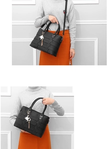 Macro shot of black woven texture tote bag featuring a cute cat-shaped metal pendant charm