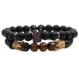 Detailaufnahme von Tigerauge- und Steinperlen-Armbändern mit goldenen Kronen-Anhängern