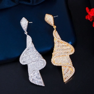 Macro detail of geometric spiral earrings with micro-paved zircons in gold and silver