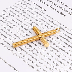 Nahaufnahme des goldenen Spiral-Kreuzanhängers mit Schraubgewinde auf Papierhintergrund