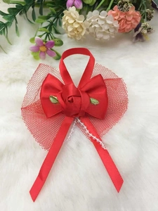 Close-up of red satin bow with handmade rose, green leaves and hanging pearl beads