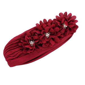 Détail du turban bordeaux avec fleurs en tissu et finitions de perles nacrées