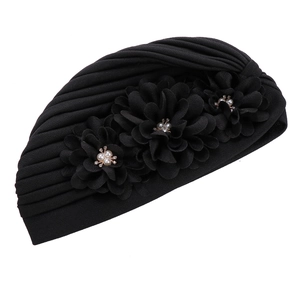 Détail du turban noir avec trois fleurs 3D ornées de perles et de strass scintillants