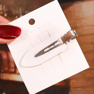 Detail einer minimalistischen weißen ovalen Haarklammer mit silbernem Entenschnabelclip