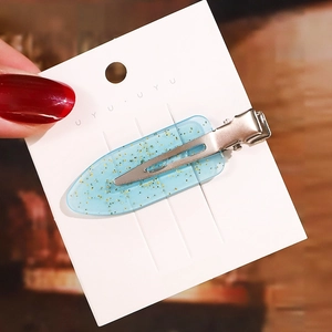 Detail einer himmelblauen transparenten Haarspange mit Goldglitzer auf Displaykarte