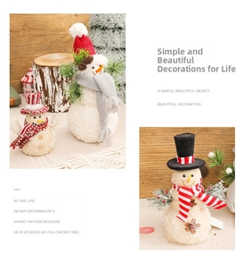 Close-up of plush Christmas snowman figurines with red knit caps and pine needle accents
