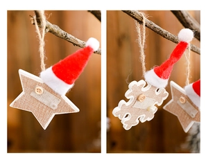 Detail of wooden Christmas star and snowflake ornaments with red plush hats on branches
