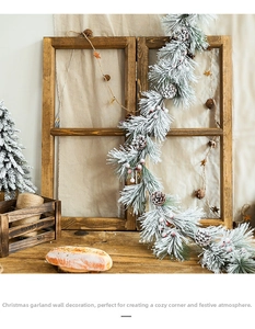 Close-up of Christmas garland with artificial snow, pine cones, and red berries on wood