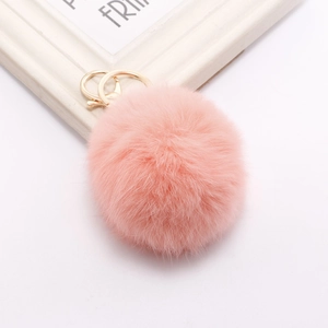 Close-up of a pink faux rabbit fur pom pom keychain with a polished gold metal clasp