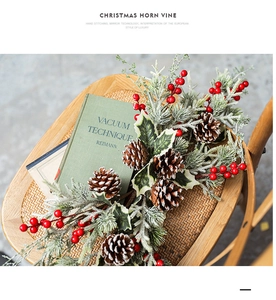Christmas horn vine with red berries and pine cones draped over a vintage wooden chair