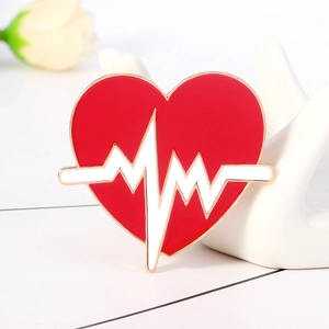 Broche cœur en émail rouge avec ligne ECG présentée sur un support de main en céramique