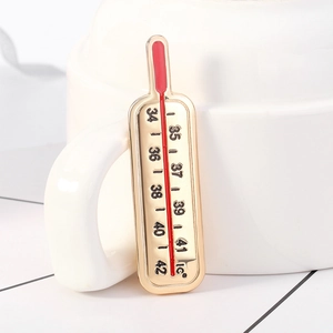 Vue macro détaillée d'une broche thermomètre en émail avec des bords en alliage doré