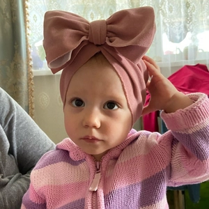 Close-up of baby turban hat featuring a large soft bow decoration in dusty pink