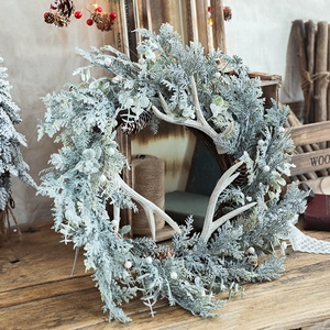 Winter Christmas wreath with snowy cedar branches, pine cones and decorative antlers