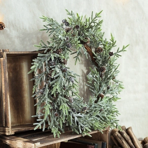 Nordic Christmas wreath with pine branches, cones and white snow finish on wooden background