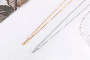 Flat lay of gold and silver double-layered cross necklaces with magazine and glass accents