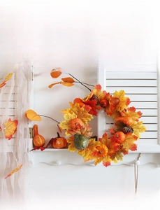 Close-up of Halloween wreath with faux pumpkins, pine cones, and orange maple leaves