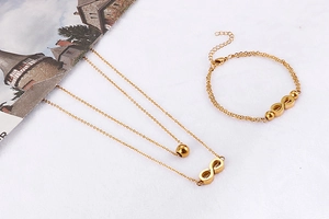 Detailed view of gold double-layer necklace and bracelet set with infinity charms