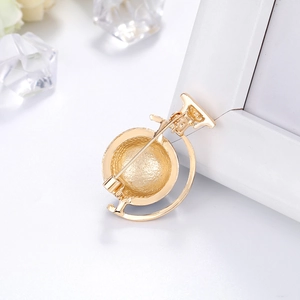 Detail view of the golden globe brooch back showing metal texture and pin fastening