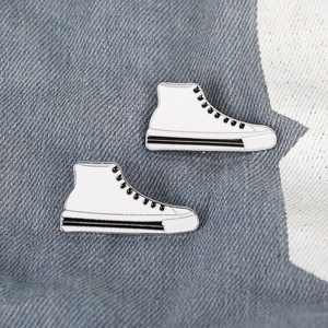 Pair of creative white high-top sneaker enamel pins on blue star denim fabric