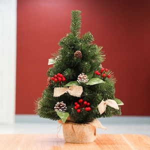Mini tabletop Christmas tree with red berries, pinecones, and burlap base on wood
