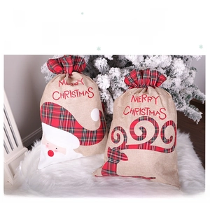 Close-up of burlap Christmas gift bags with Santa and Reindeer appliques and plaid drawstrings