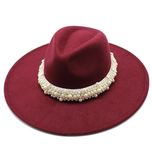Detail of burgundy wool fedora hat with elegant white pearl trim around the wide brim