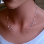 Close-up of silver double-layer necklace featuring minimalist hollow leaf pendants