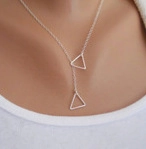 Close-up of a silver double triangle necklace on model with minimalist geometric pendant