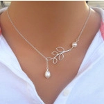 Detail shot of silver necklace with delicate leaf pendant and pearls on model neck