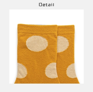 Detail view of yellow knit socks with beige polka dots showing fabric texture and cuff