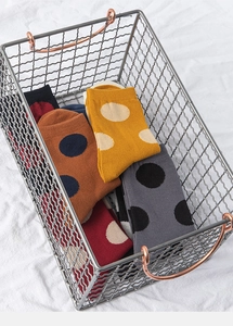 Close-up of colorful polka dot cotton socks in a metal mesh basket with bronze handles