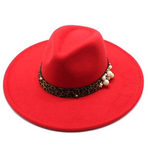 Detail of red wool fedora featuring leopard print band, pearls, and gold rivet accents