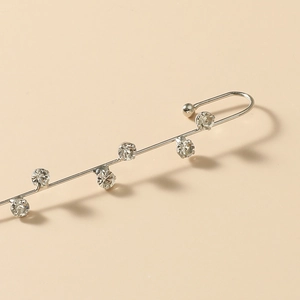 Macro view of silver crawler earring with sparkling cubic zirconia on beige background