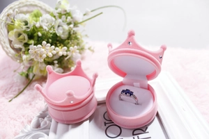 Pink crown-shaped velvet jewelry box for rings displayed with elegant dried flowers