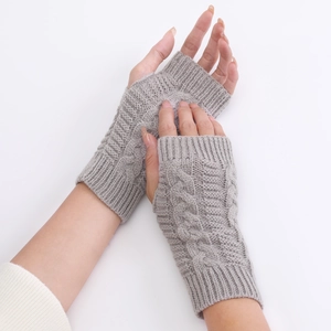 Detailed close-up of grey cable-knit fingerless gloves showing premium texture and pattern