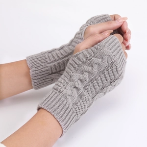 Close-up detail of grey knitted fingerless gloves with a classic cable knit pattern texture