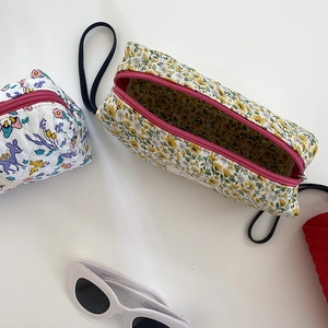Dettaglio di pochette trapuntate in cotone a fiori con cerniere rosa e laccetto nero