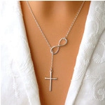 Detail of silver infinity symbol necklace with cross pendant on model wearing lace