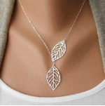 Detail shot of a silver-tone double leaf pendant necklace worn on a woman's neck