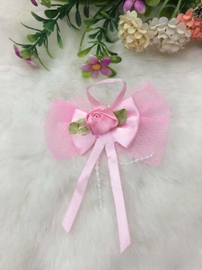 Close-up of handmade pink satin rose bow with ribbons and delicate pearl beads
