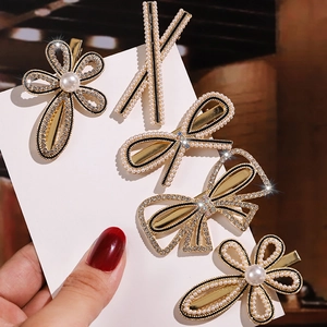 Set of five elegant gold hair clips with white pearls and diamonds in floral bow designs