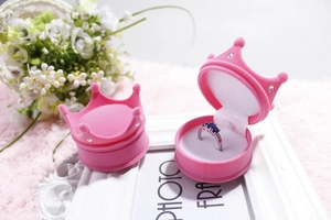 Detailed view of pink crown-shaped velvet jewelry box featuring a sapphire ring insert