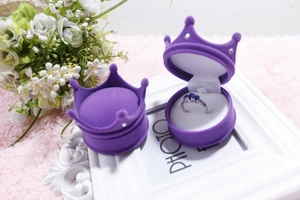 Detailed view of crown shaped purple jewelry box with a ring inside on floral background