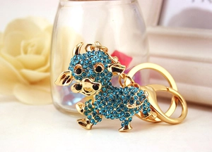 Dettaglio del portachiavi a forma di mucca dorata con strass blu e chiusura a moschettone